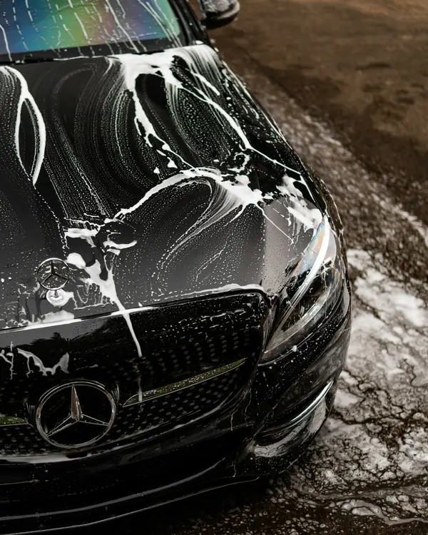 Snow foam running down the bonnet of a black car