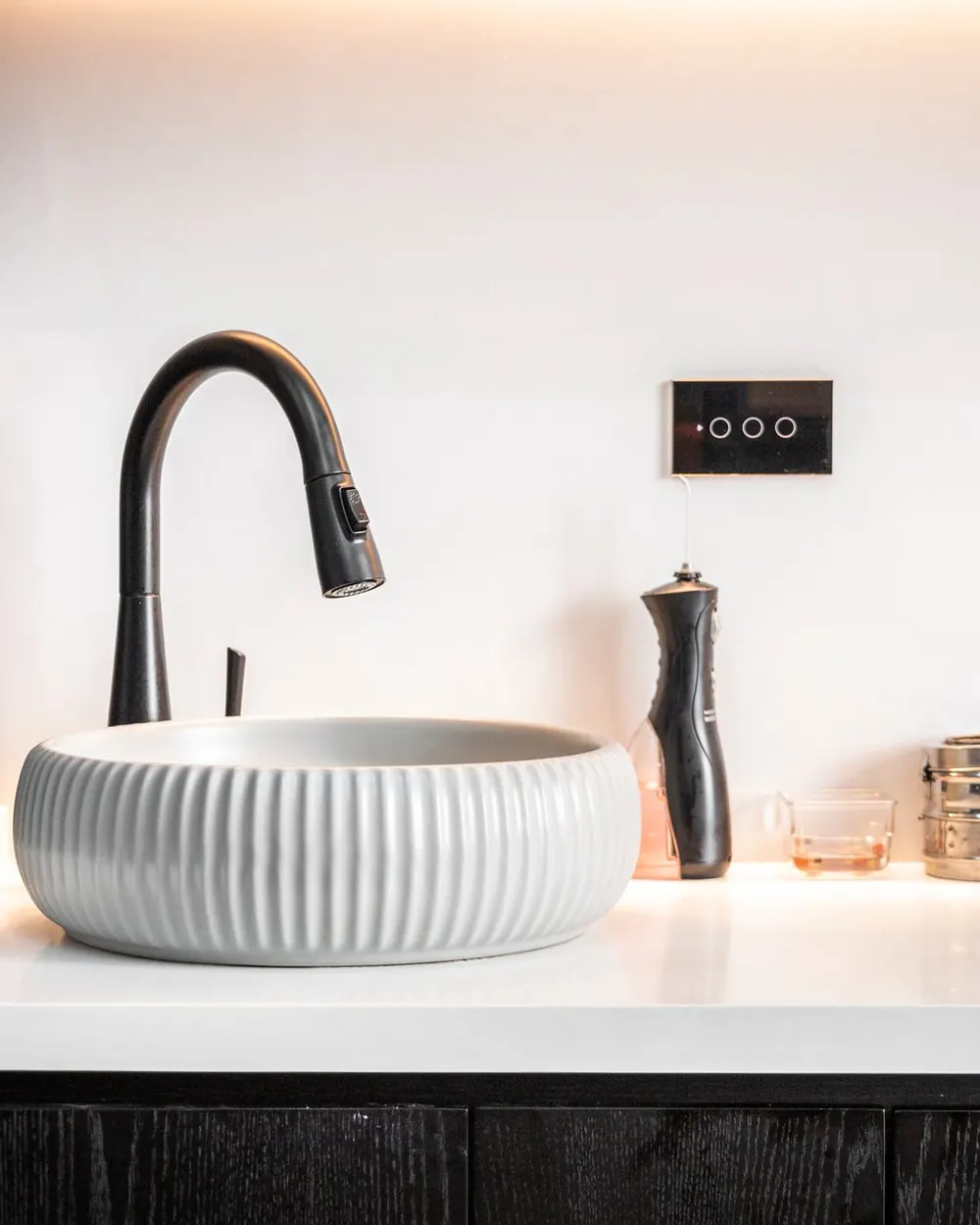 A ribbed white basin and black faucet on a clean bathroom counter