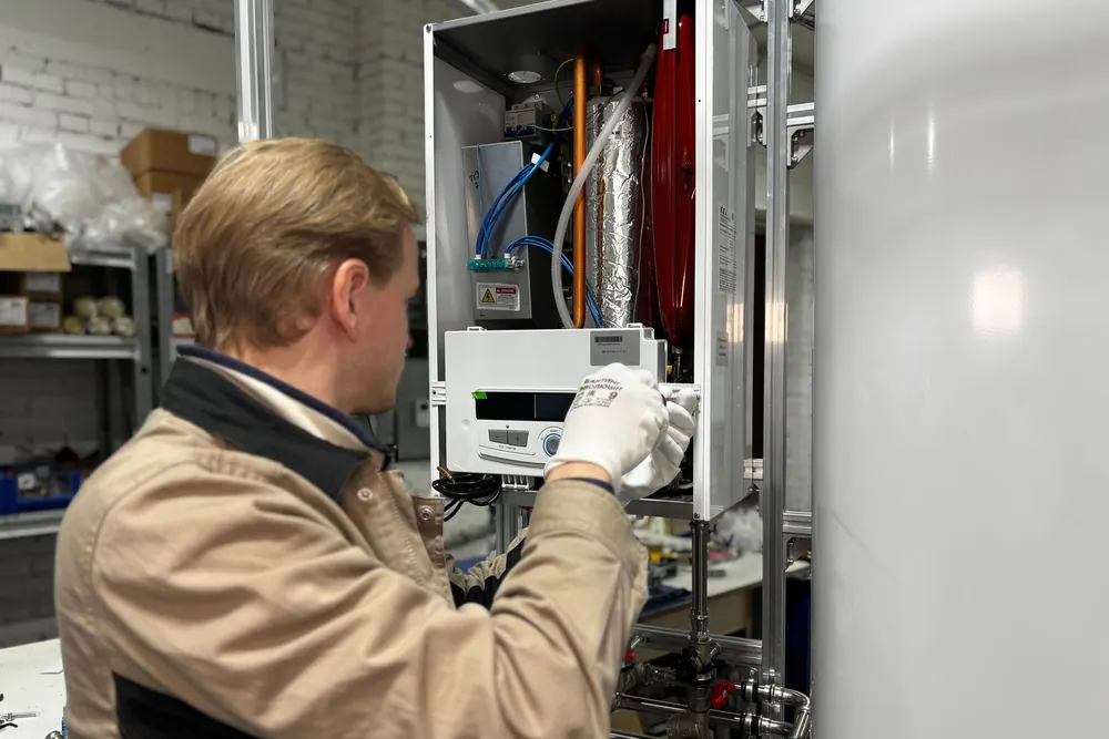 A technician adjusting the controls of a wall-mounted water heater
